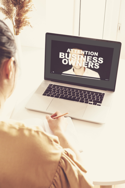 The back of a woman who is watching a video sales message on a laptop.